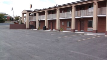 Un motel de varios pisos con estacionamiento al frente.