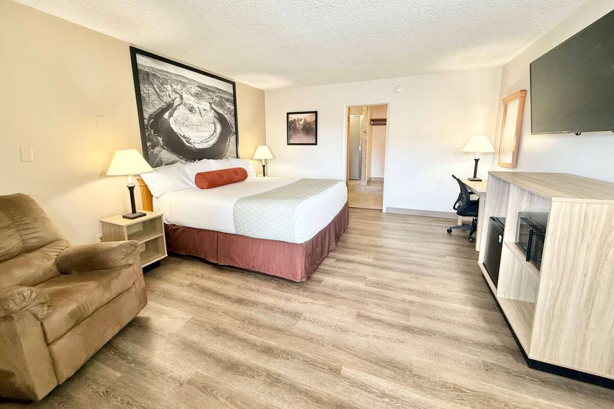 A hotel room with a bed, a sofa, a desk, and a TV.