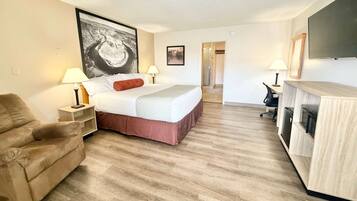 A hotel room with a bed, a sofa, a desk, and a TV.