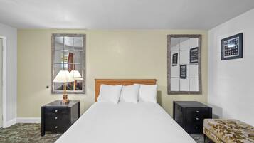 A hotel room with a bed, two nightstands, a lamp, a mirror, and a sofa.