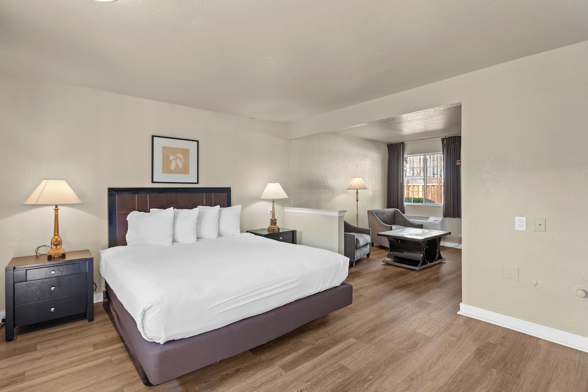 A hotel room with a large bed, two bedside tables with lamps, a desk, and a chair.