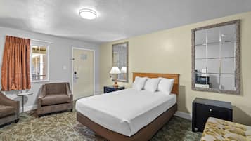 Una habitación de hotel con una cama, dos mesitas de noche, una silla, un espejo y una puerta.