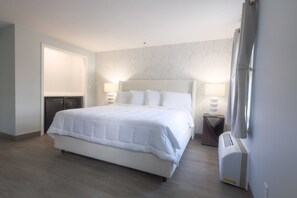 A neatly arranged hotel room with a large bed, bedside lamps, a heater, and a wardrobe.
