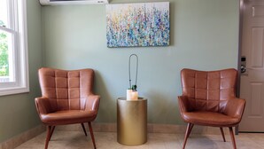 Two leather armchairs, a textured gold side table with a candle, and a colorful abstract painting on the wall. - Westborough Inn (Westborough)