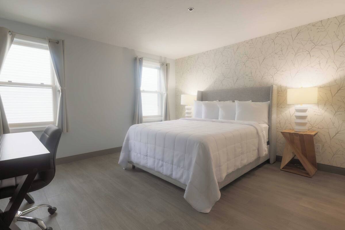 A hotel room with a bed, a desk, and a lamp.