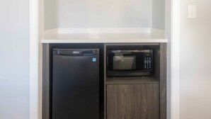 A compact kitchenette with a refrigerator and microwave. - Westborough Inn (Westborough)