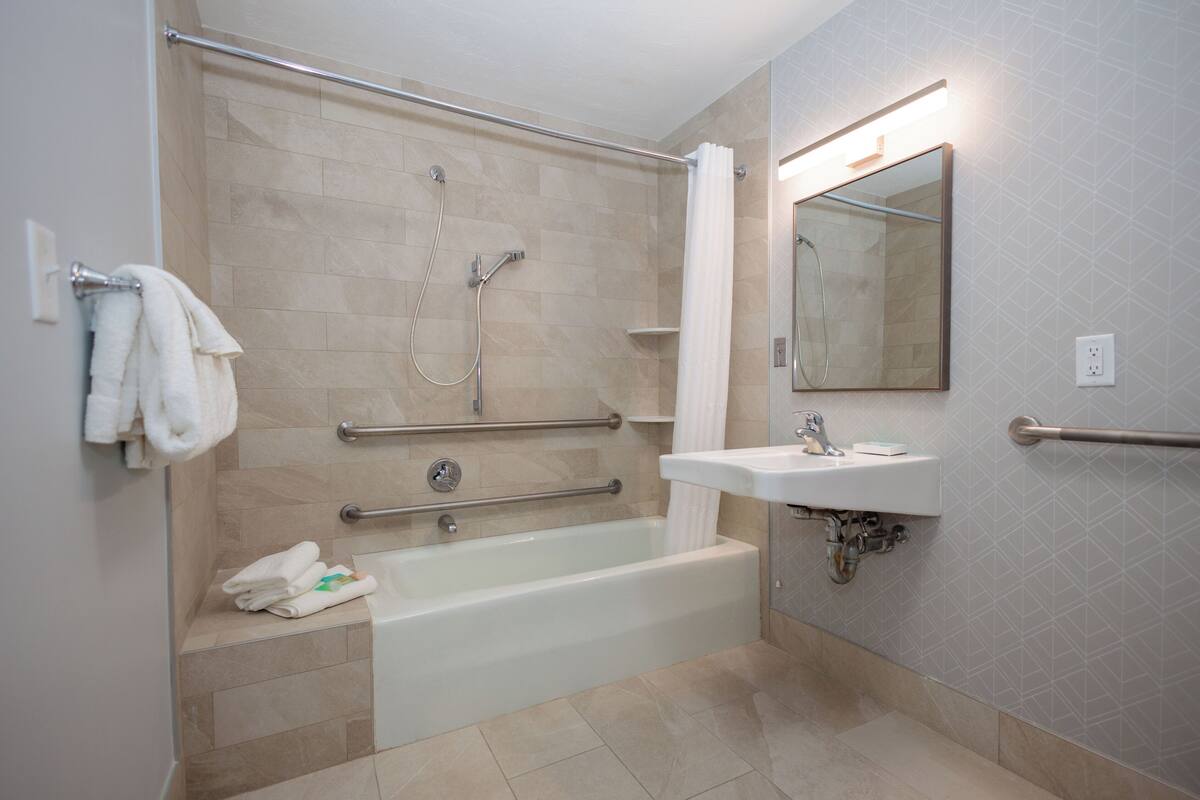 A modern bathroom with a bathtub, shower, and sink.
