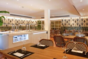 Enjoy dining in a stylish space with a central island, wooden tables, and decorative wallpaper.