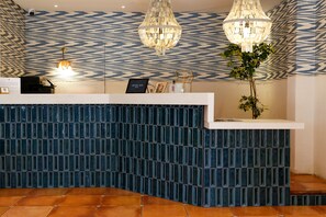 Welcome to our reception area, featuring a stylish desk with a potted plant and geometric patterned wallpaper.