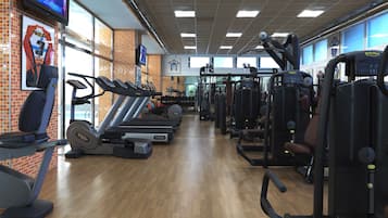 Un gimnasio con cintas de correr, máquinas de pesas y equipo de ejercicio.