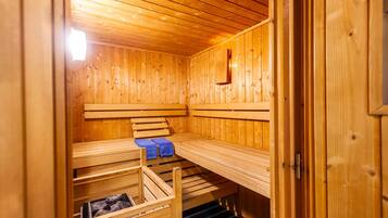 A wooden sauna with benches and a bench with towels.