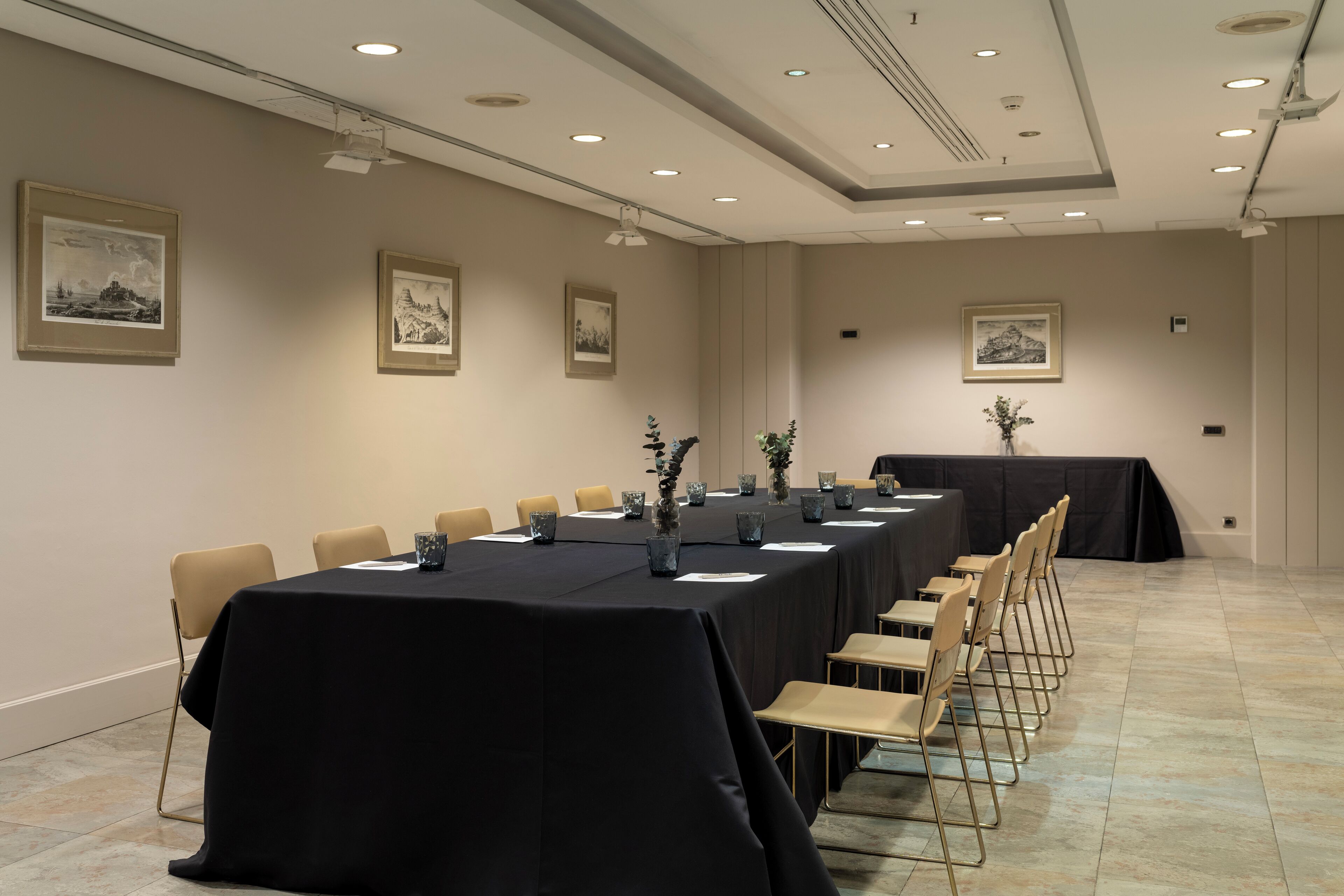 A conference room with a long table, chairs, and framed pictures on the walls.