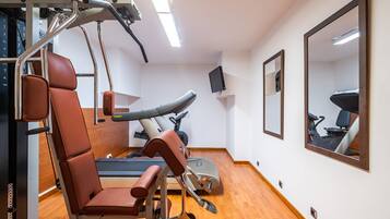 A gym with exercise equipment, a treadmill, and a mirror on the wall.