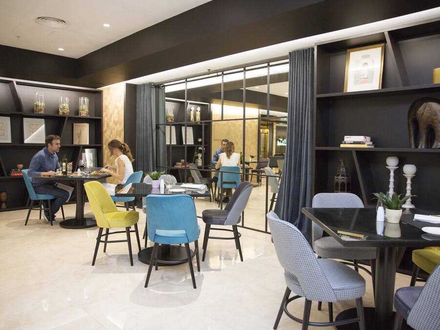 A modern dining area with round tables and chairs, a black and white color scheme, and decorative items on shelves.