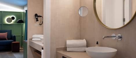 A modern bathroom with a large round mirror, a white vessel sink, and a towel rack.