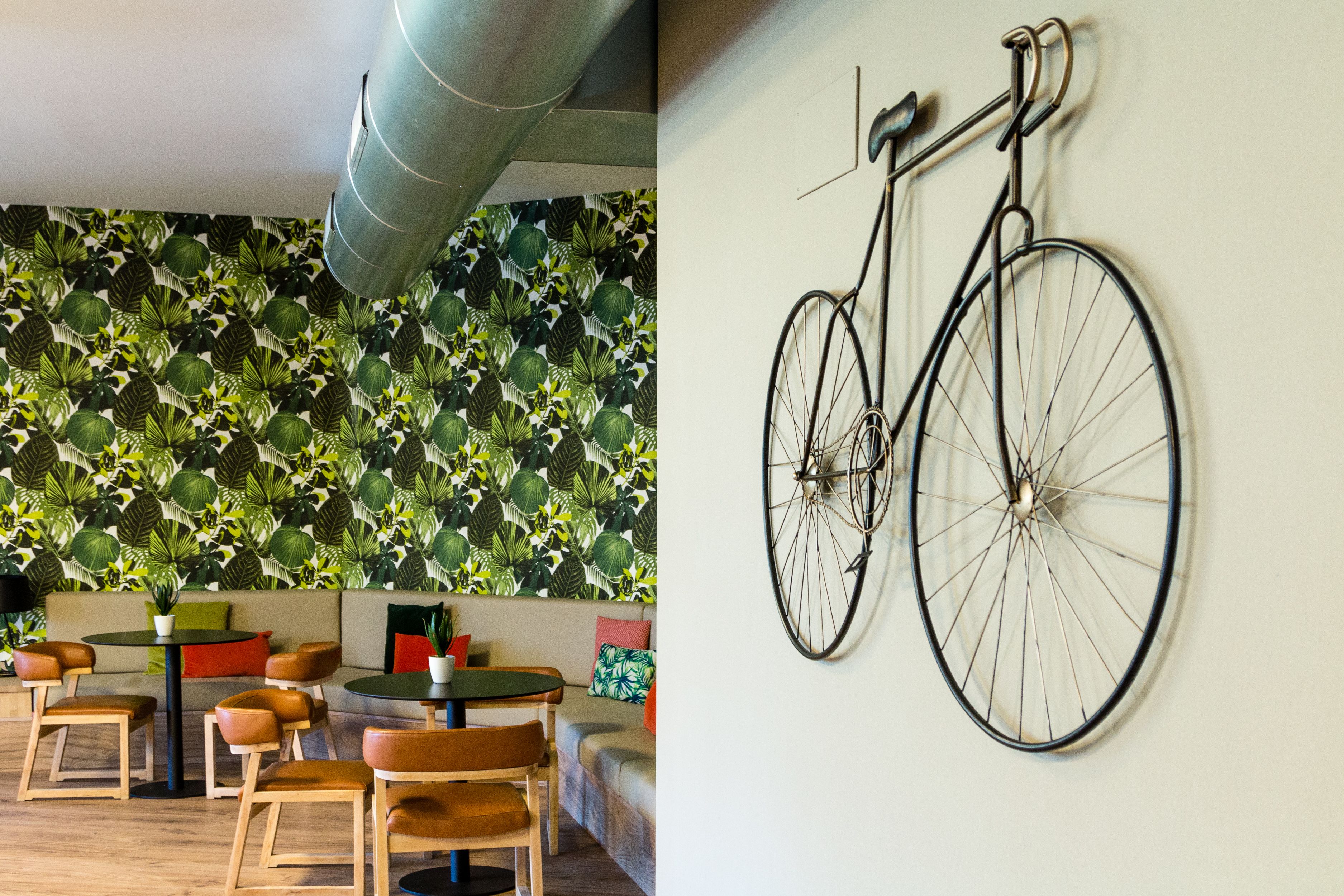 Una habitación con pared estampada, una bicicleta colgada en la pared y un espacio de descanso con sillas y una mesa.