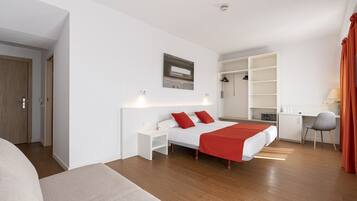 A modern hotel room with a large bed, a desk, and a wardrobe.