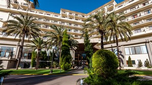 Et hotel med flere etager, altaner, palmer og en velholdt græsplæne.