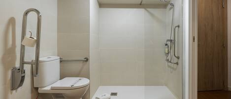 A modern bathroom with a toilet, a shower with a glass door, and a wooden floor.