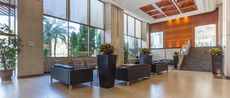 Um hall amplo com grandes janelas, escada e áreas de estar modernas.