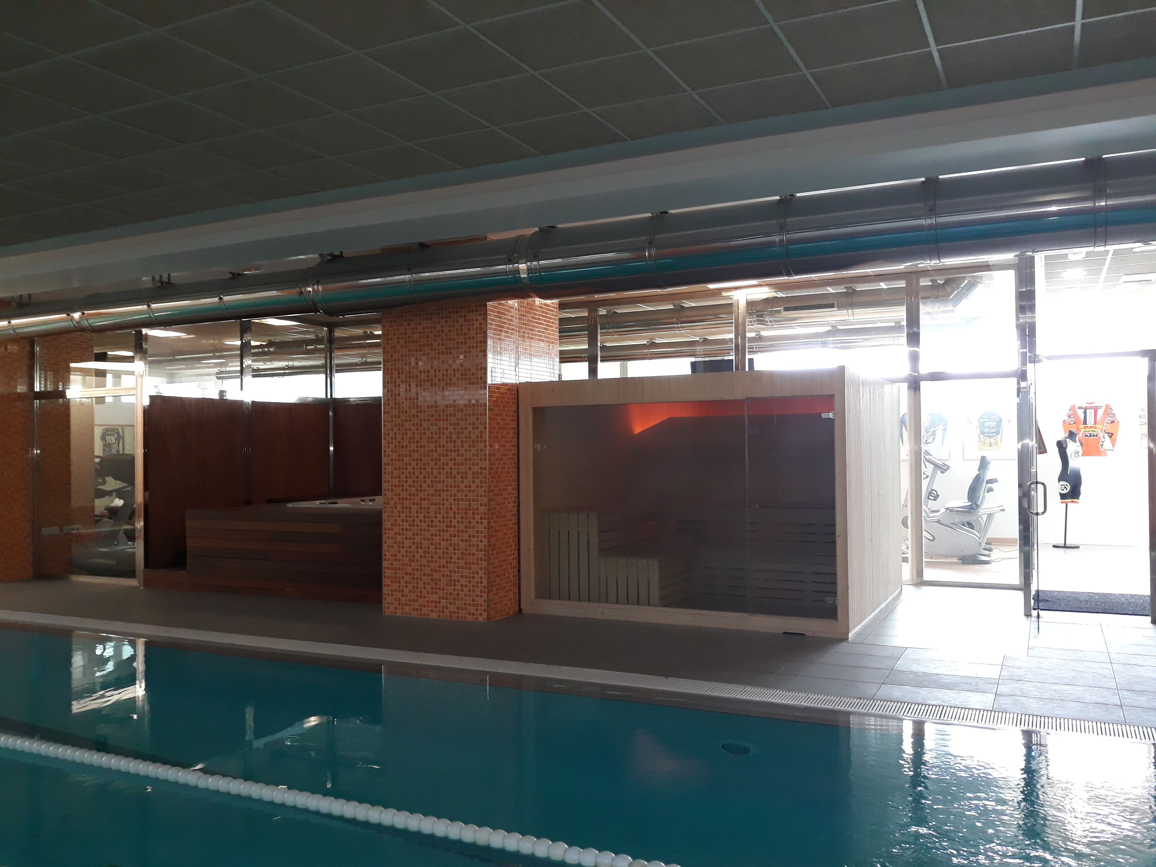 Una piscina interior con carriles delimitados, suelo de baldosas y pared divisoria de vidrio.