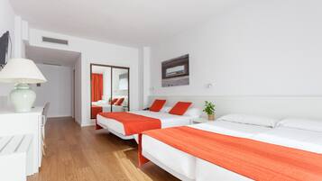 Ein Hotelzimmer mit zwei Betten, einem Schreibtisch, einer Lampe, einem Spiegel und einem Bild an der Wand.