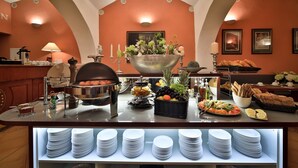 Un buffet proposant une variété de plats, un coin café et une présentation d’assiettes.