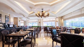 A spacious restaurant with high ceilings, chandeliers, and large windows. - Grand Noble Hotel (Dongguan)