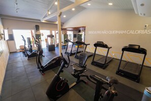 Ett gym med olika typer av konditionsmaskiner, inklusive löpband och motionscyklar, samt en vägg med motiverande texter.