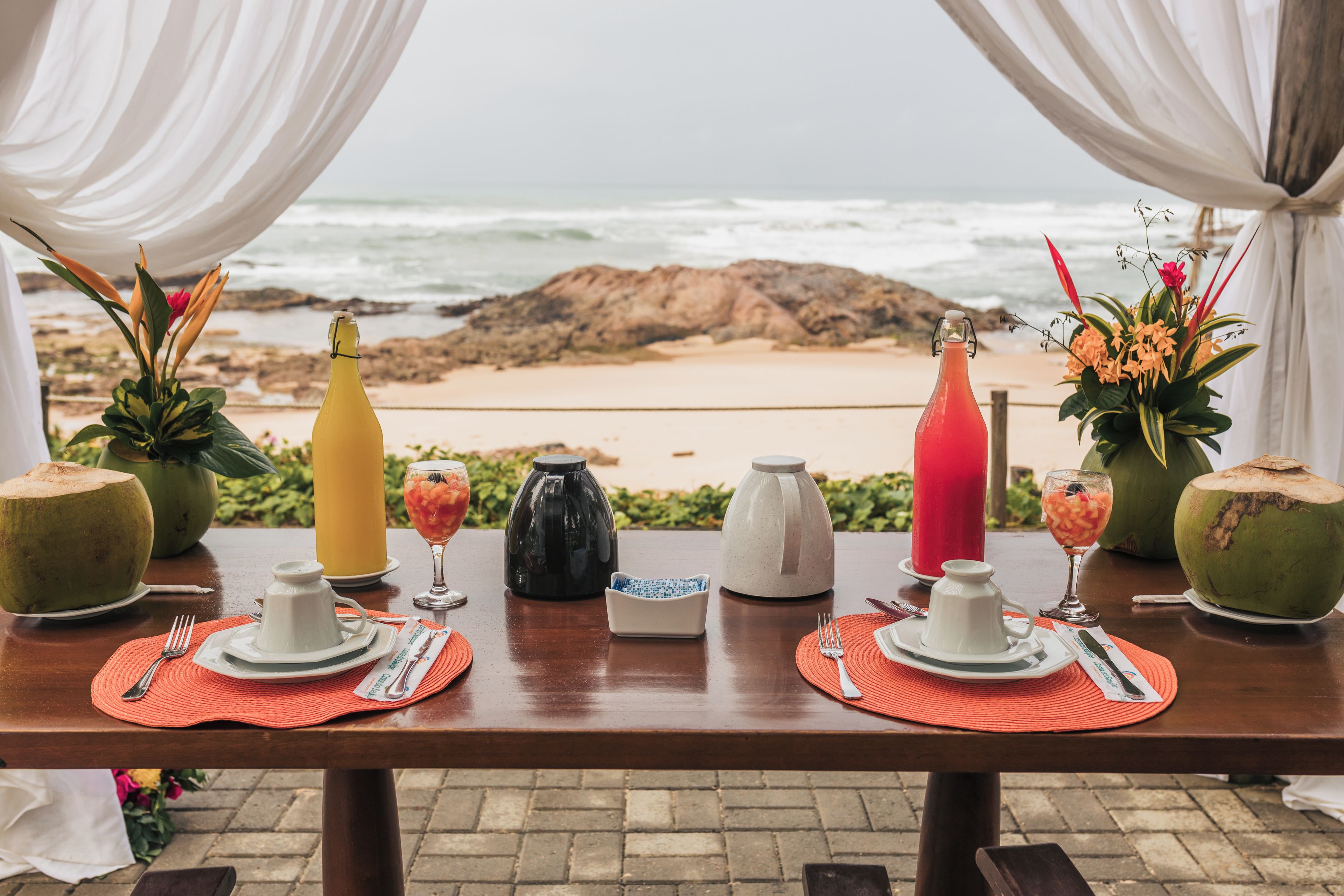 A table set for a meal with a view of the ocean and rocks.