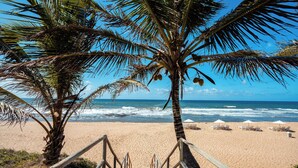 A wooden staircase leading to a sandy beach with palm trees and ocean waves in the background. - Sauipe Terra Resort - All Inclusive (Mata de São João)