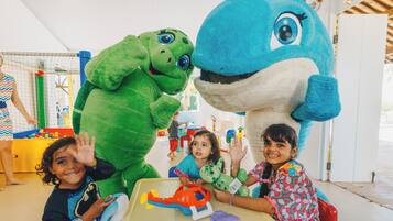 Ein Zimmer mit Spielbereich, darunter ein Tisch mit Spielzeug und ein großes aufblasbares Dinosaurier.