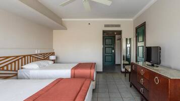 A hotel room with two beds, a ceiling fan, a TV, and a wooden dresser.
