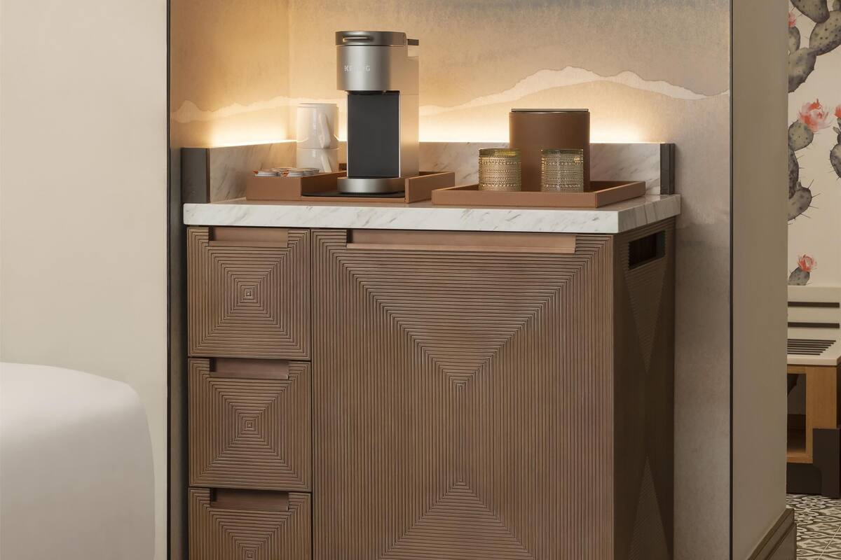 A compact kitchen with a coffee machine, a wine glass display, and a patterned backsplash.