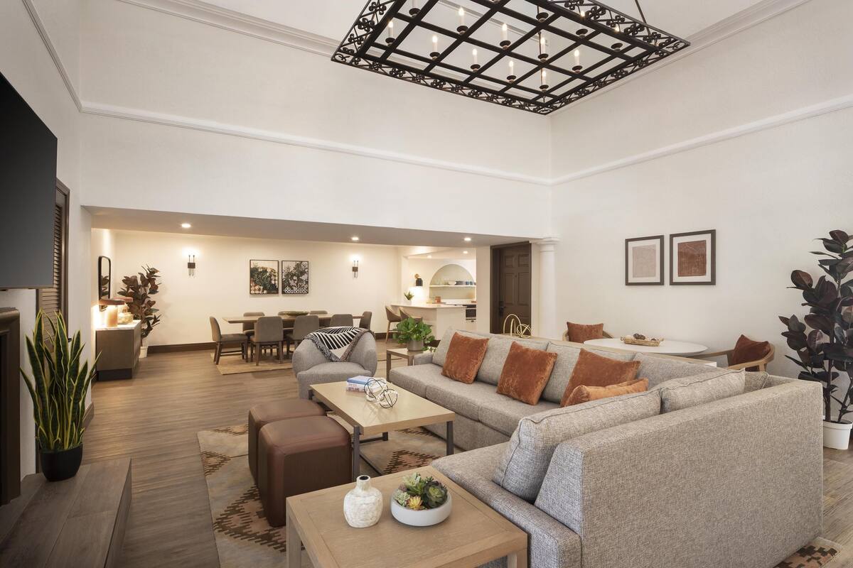 A spacious living area with a large sofa, a coffee table, and a dining area in the background.