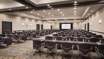 Uma grande sala de conferências com fileiras de mesas e cadeiras, equipada com garrafas de água e uma tela de projetor exibindo "The Scottsdale Resort & Spa".