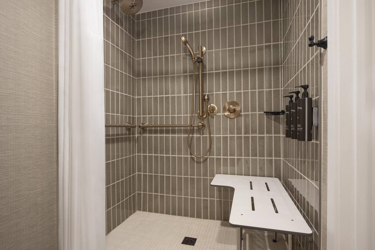 A modern bathroom with a shower, a sink, and a towel rack.