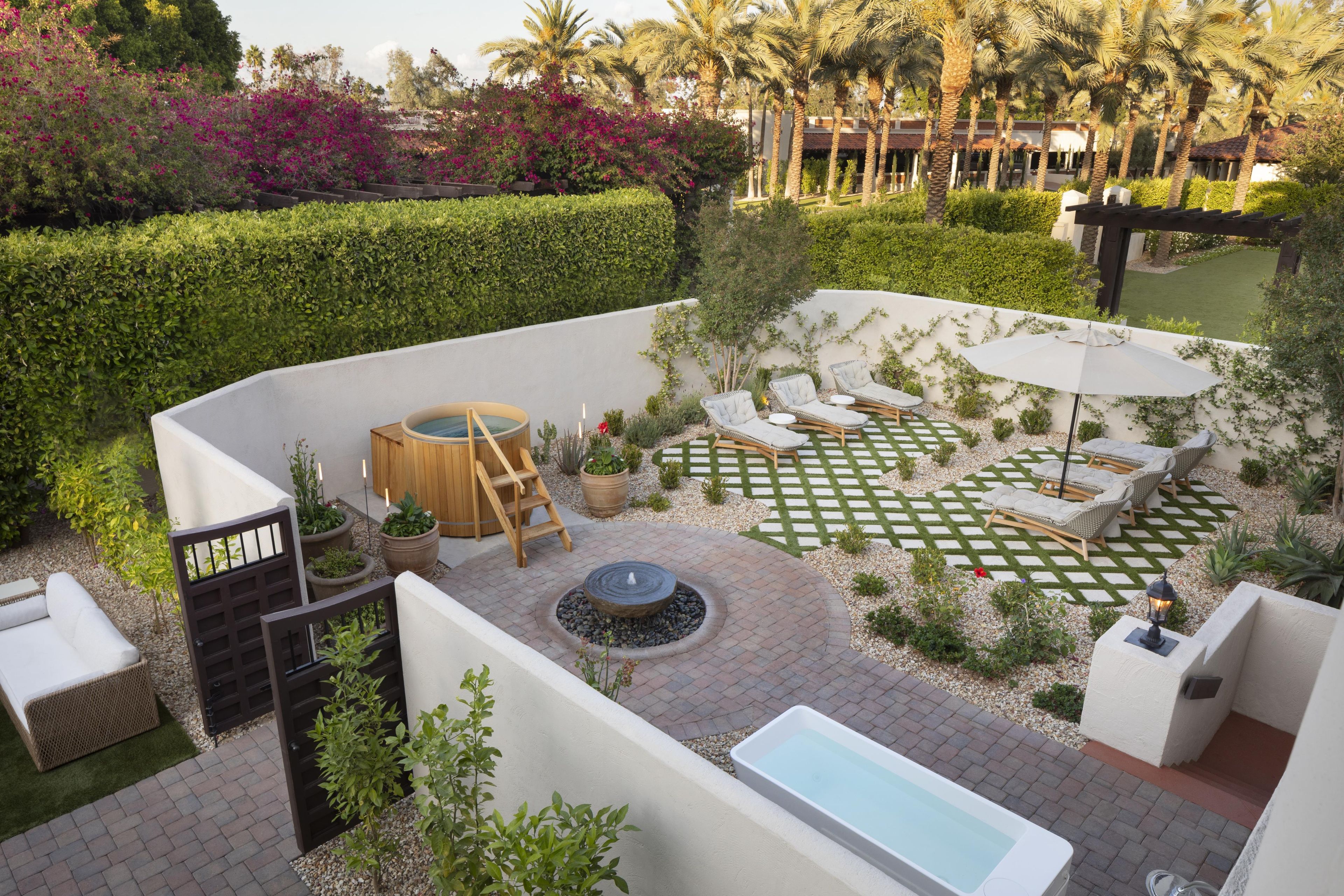 A landscaped outdoor area with a hot tub, lounge chairs, and a small pool.