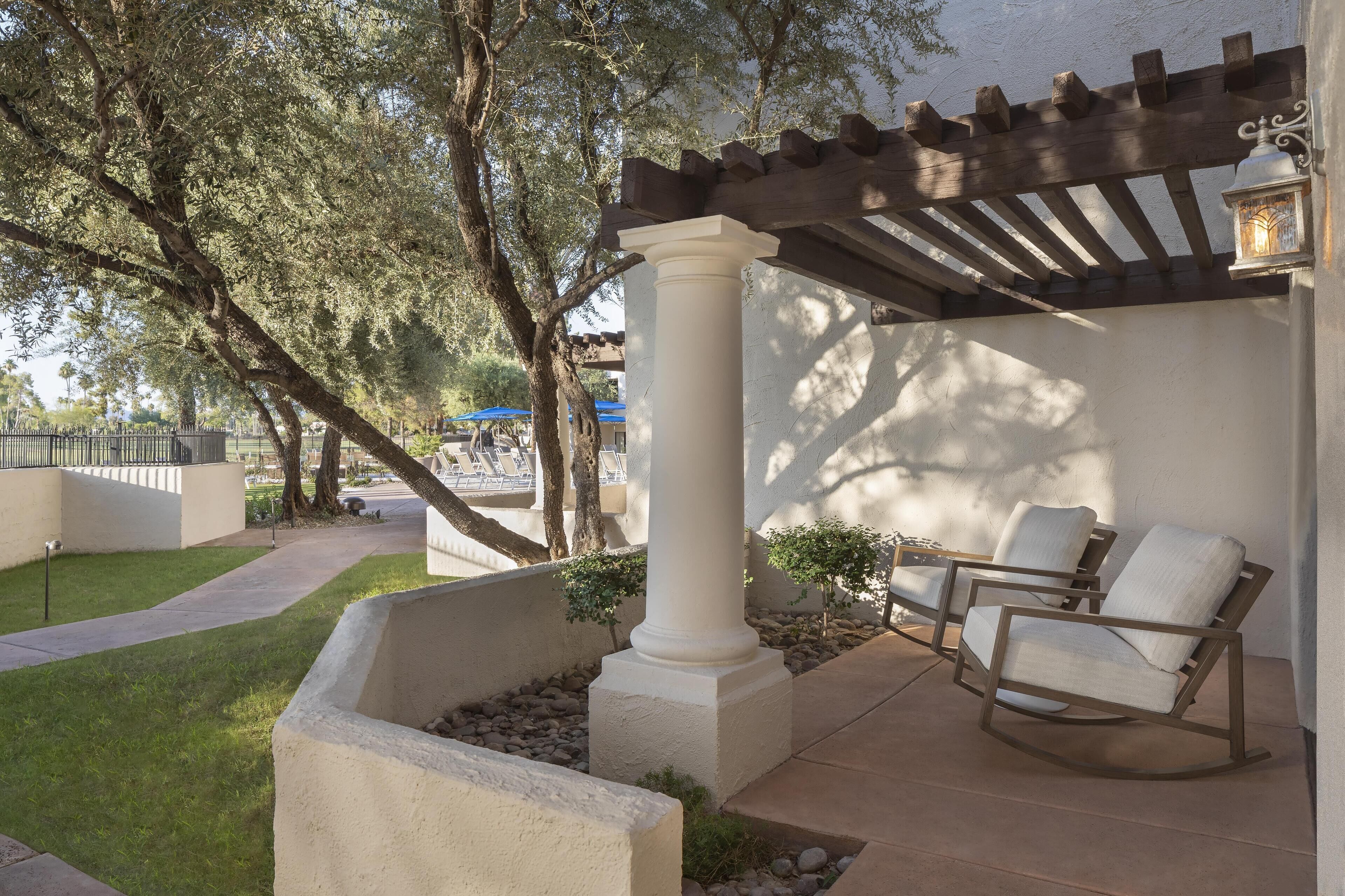 A patio area with a pergola, white columns, and two rocking chairs.