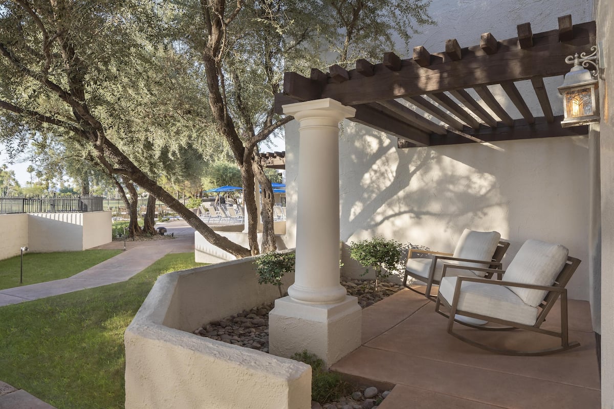 A patio area with a pergola, white columns, and two rocking chairs.