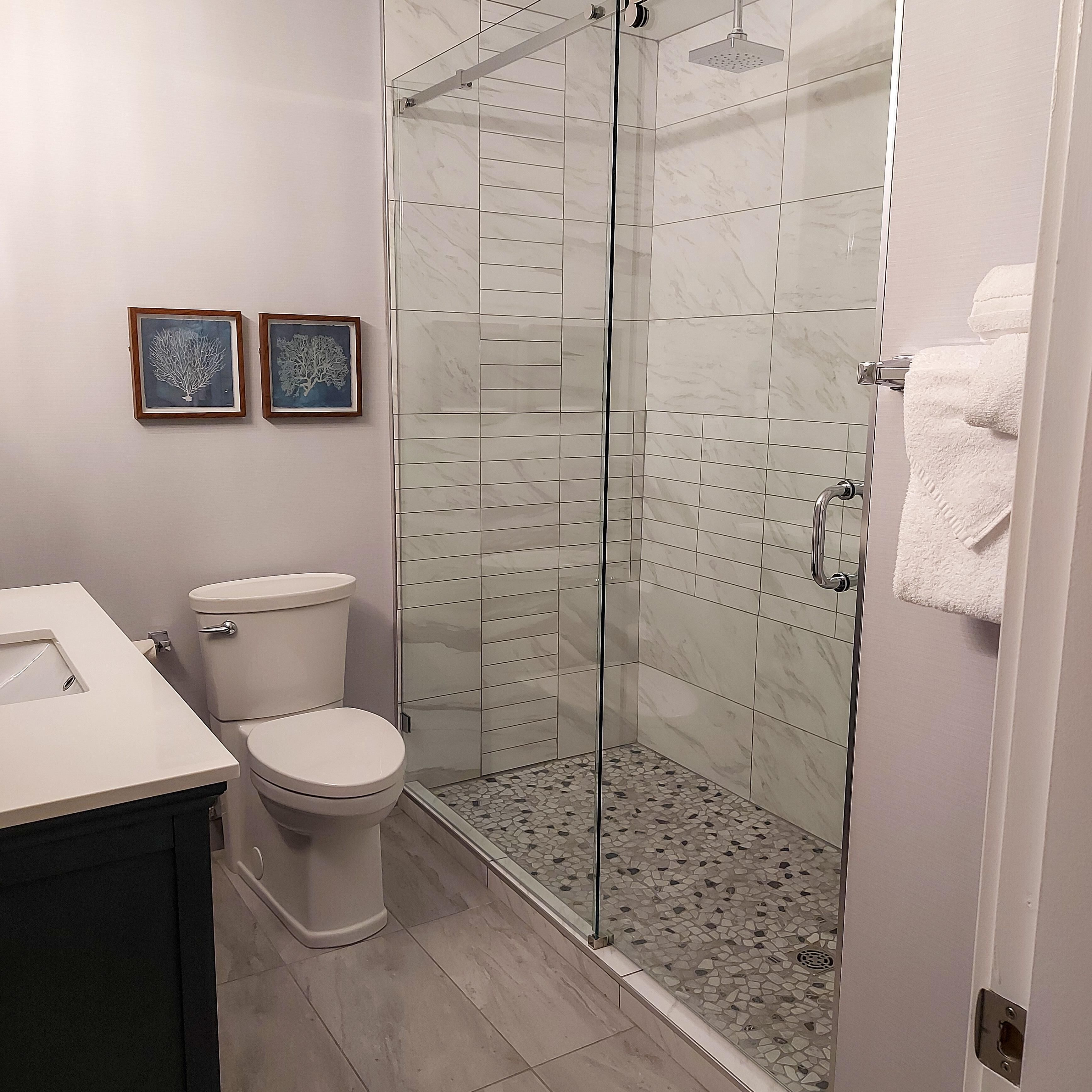 A modern bathroom with a glass-enclosed shower, a toilet, and a sink.
