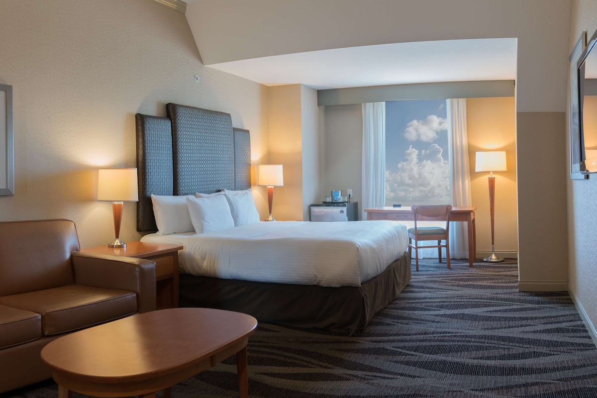 A hotel room with a bed, a sofa, a small table, a desk, and a TV.
