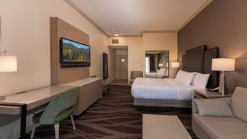 Una habitación de hotel con una cama, un escritorio, una silla, un sofá y un televisor.
