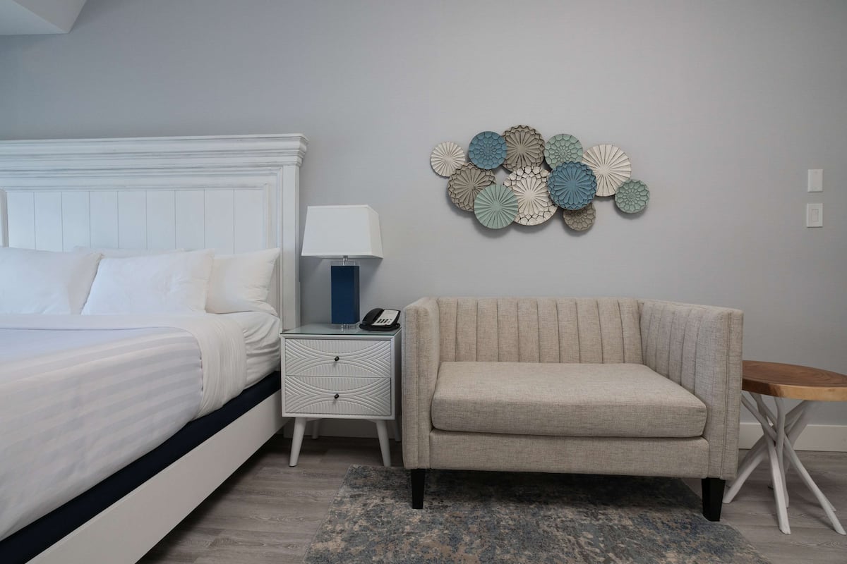 A bedroom with a bed, nightstand, lamp, and decorative wall art.