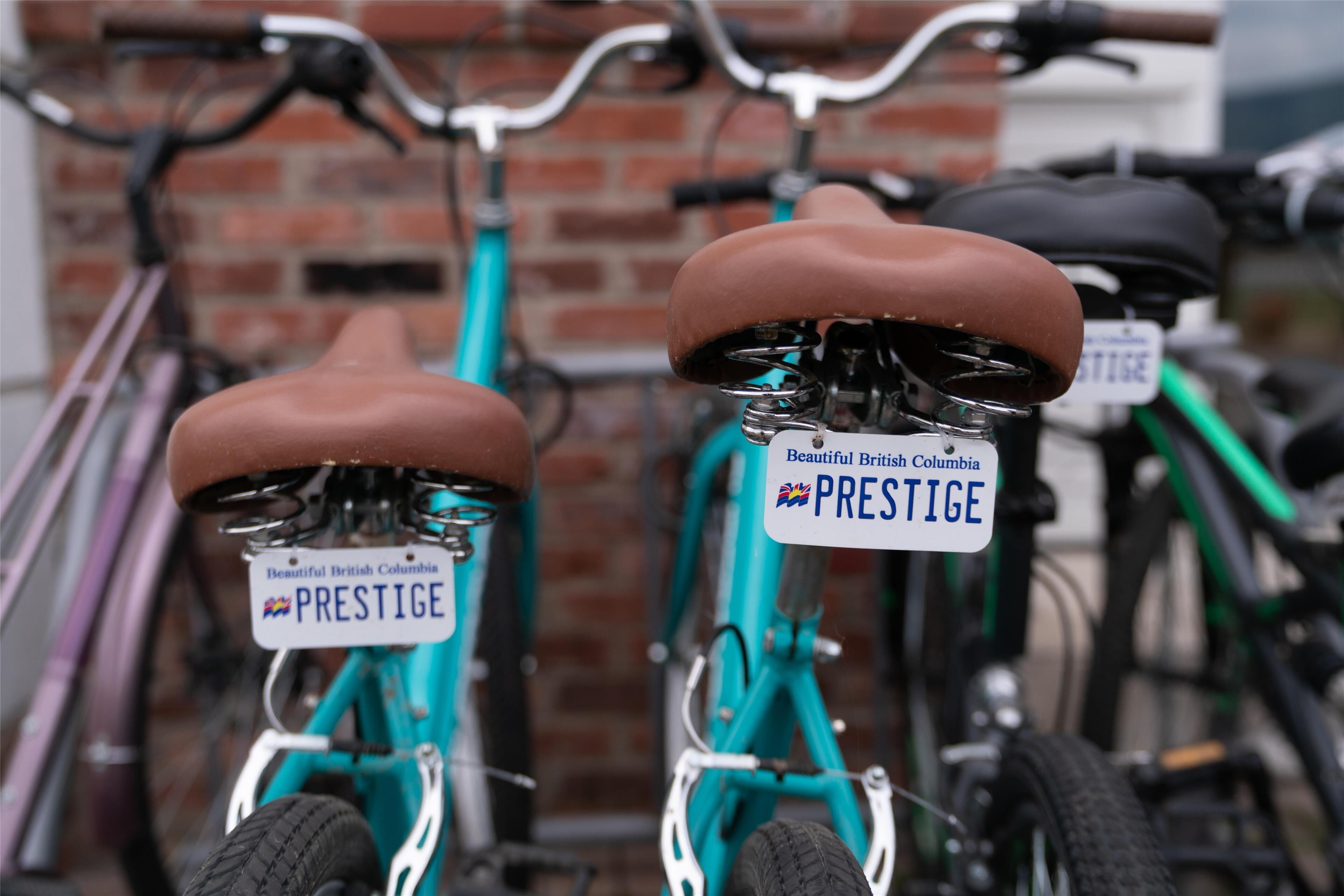 Zwei Fahrräder mit 'PRESTIGE' Kennzeichen an einer Ziegelwand geparkt.