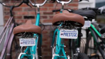 Zwei Fahrräder mit 'PRESTIGE' Kennzeichen an einer Ziegelwand geparkt.