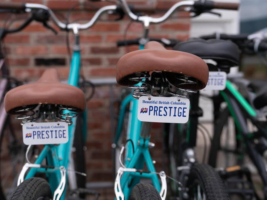 Zwei Fahrräder mit 'PRESTIGE' Kennzeichen an einer Ziegelwand geparkt.