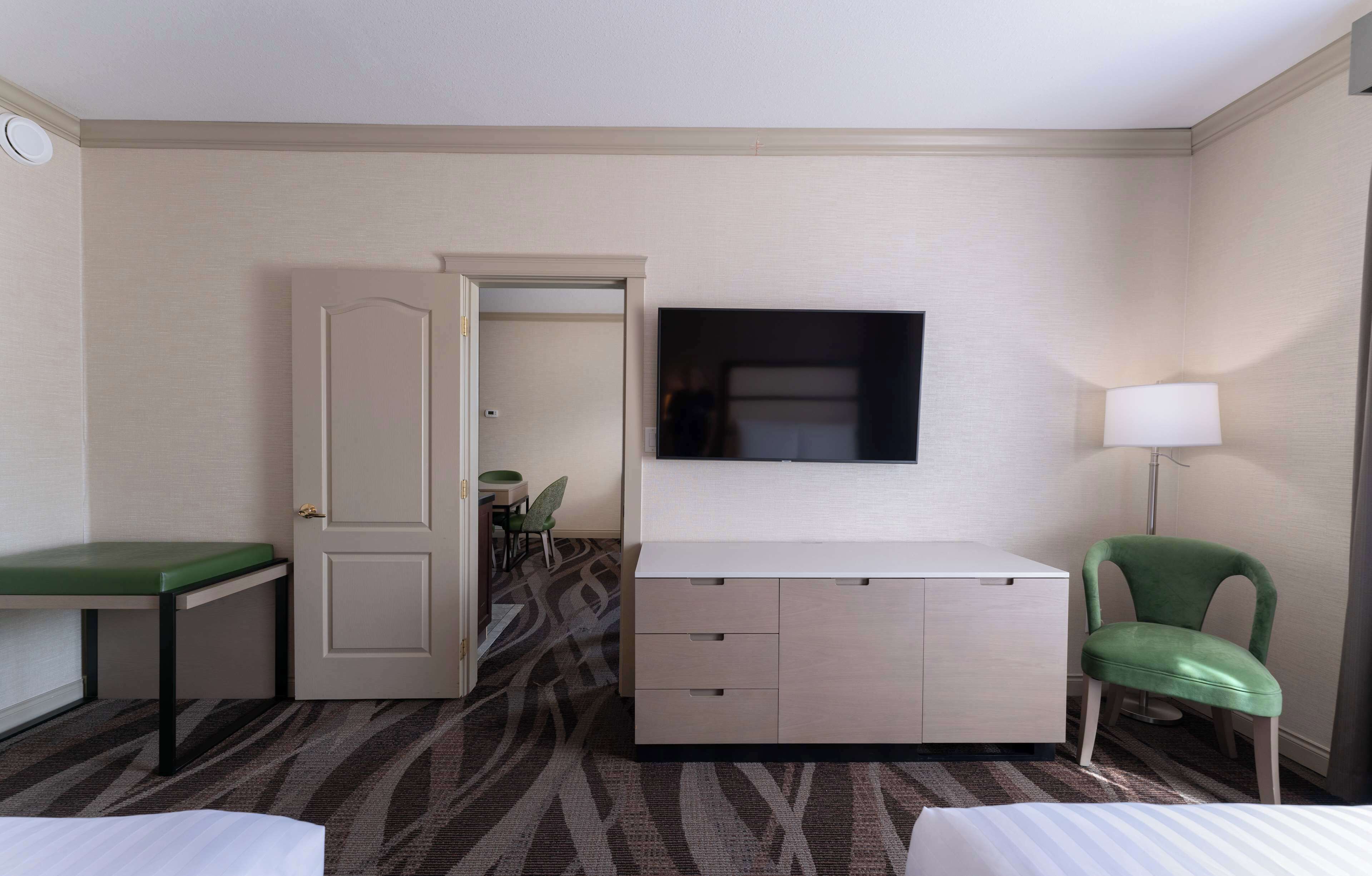 Een hotelkamer met een bed, een bureau met lades, een stoel, een televisie en een lamp.