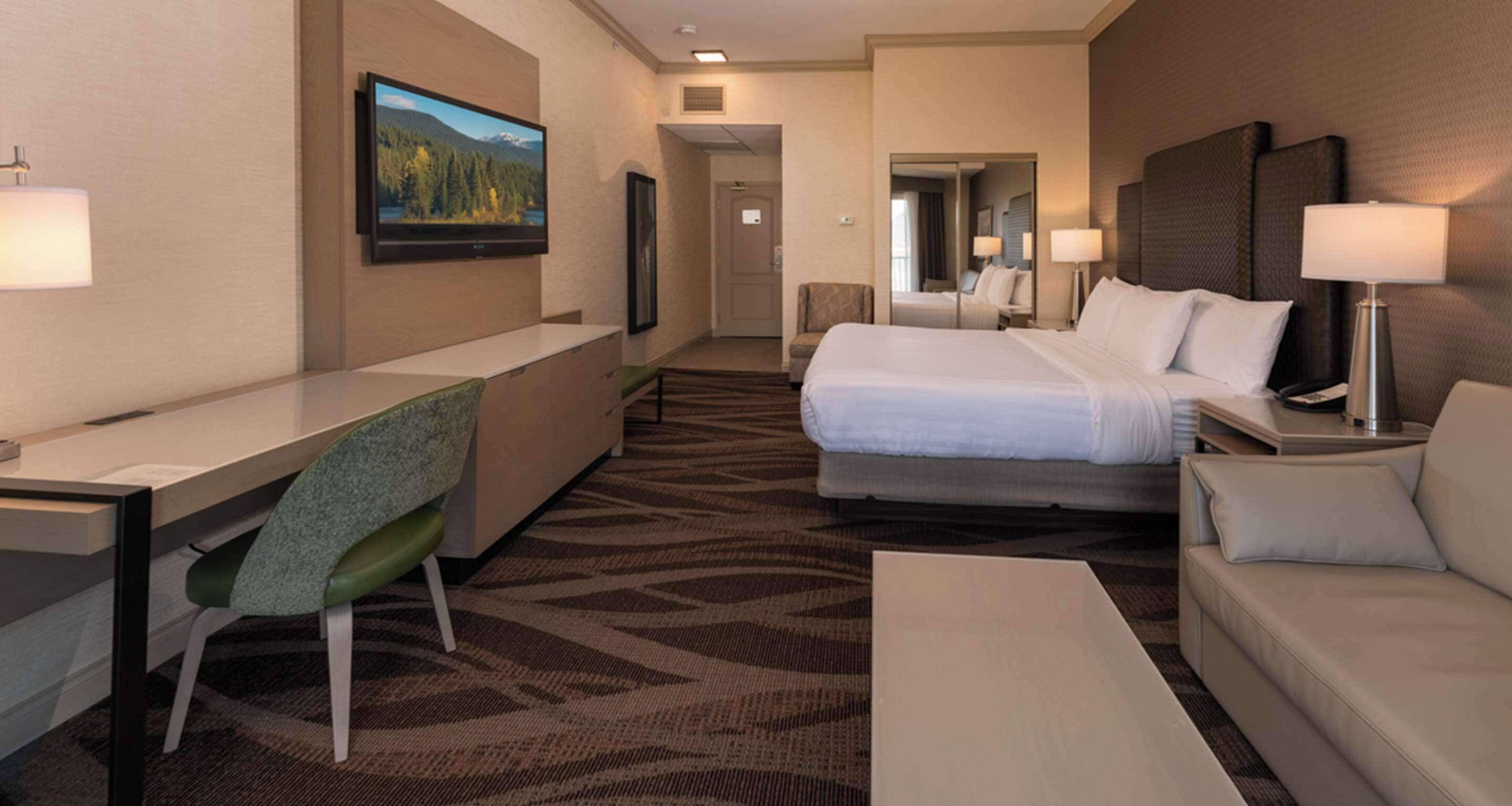 Een hotelkamer met een bed, een bureau, een stoel, een bank en een televisie.