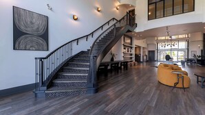 Un intérieur spacieux agrémenté d’un magnifique escalier, d’un canapé moderne et d’un grand tableau abstrait accroché au mur.